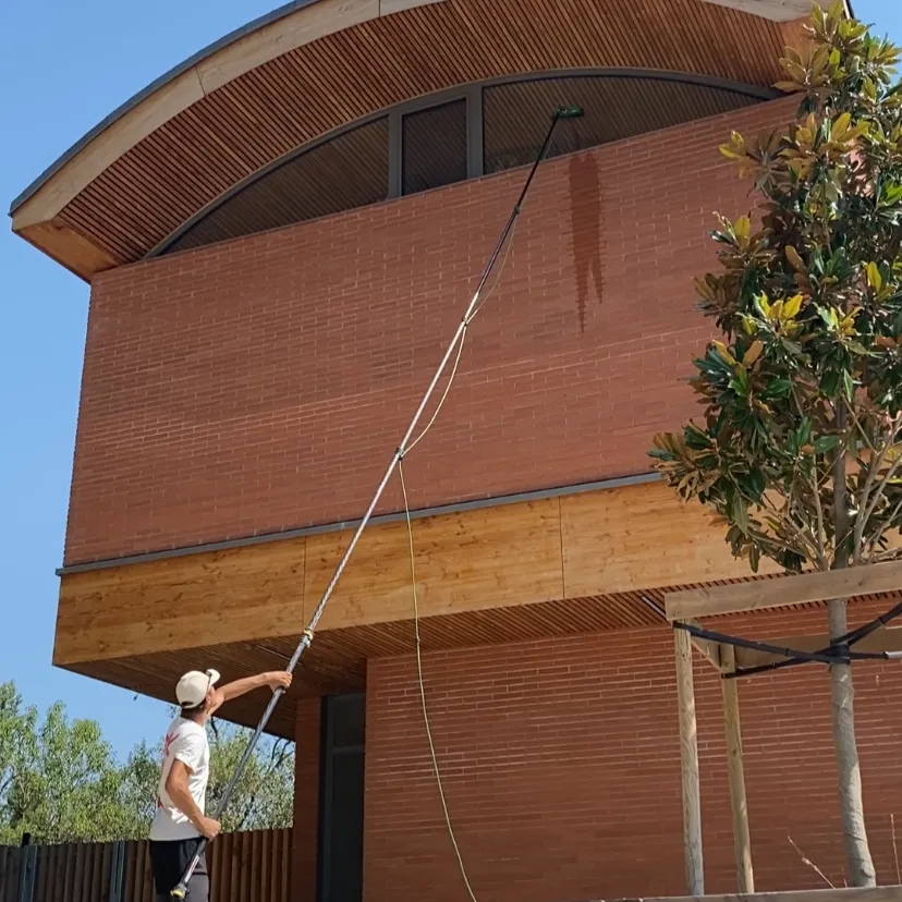 Technicien Toposmose nettoyant une façade en bois à l’aide d’une perche télescopique